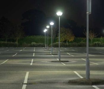 An empty parking lot/ car park at night pointlessly lit with the most harmful blue-white spectrum LED lighting